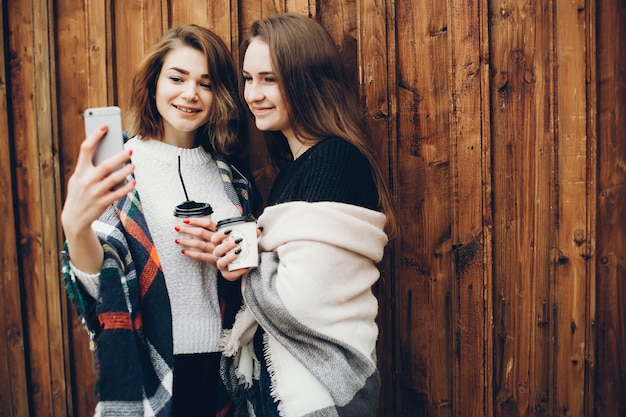 duas garotas jovens e bonitas em pé em uma cidade de primavera e bebendo café