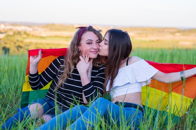 Foto duas garotas lésbicas deitado na grama com a bandeira do orgulho gay