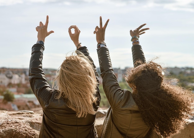 Duas garotas mostrando sinal de amor pelos dedos enquanto apreciam o conceito de horizonte da cidade