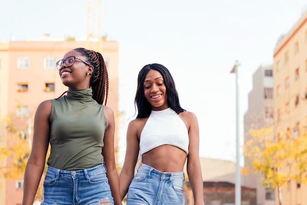 Duas garotas negras passeando felizes na cidade de mãos dadas, conceito de amor e diversidade, copie o espaço para texto