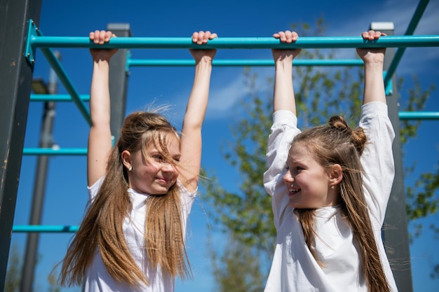 Duas garotas penduram na barra horizontal no playground