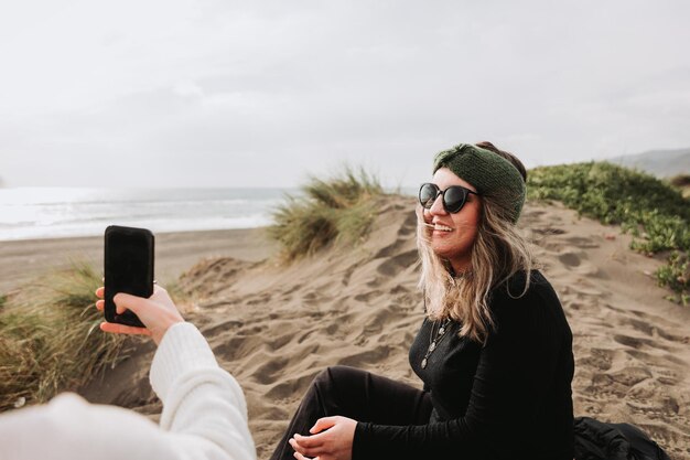 Duas garotas relaxando, sentadas e tirando fotos na praia. Superando a depressão