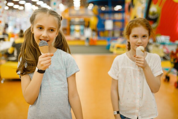 Duas garotas tomam sorvete no centro de entretenimento. lazer infantis nos feriados, felicidade infantil, crianças felizes no parquinho