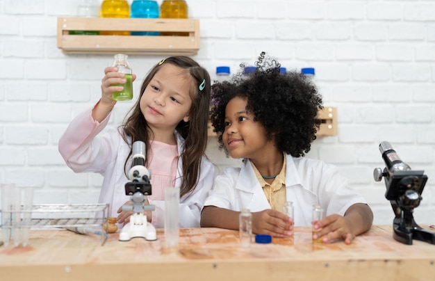 Duas garotinhas aprendendo experimento de química e segurando tubo de ensaio nas mãos na aula na escola