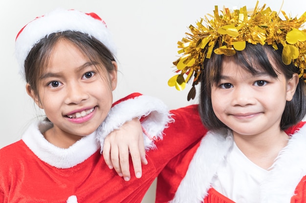 Duas garotinhas asiáticas vestindo terno vermelho de papai noel para celebrar o feriado de natal em casa