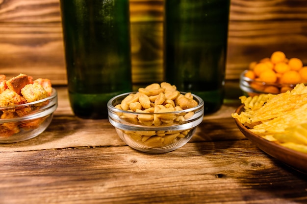 Duas garrafas de cerveja e lanches diferentes na mesa de madeira