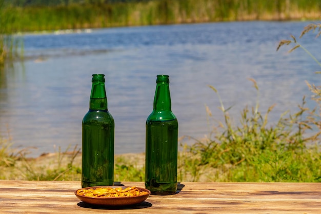 Duas garrafas de cerveja na mesa de madeira perto de um rio