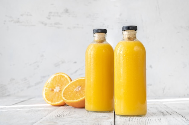 Foto duas garrafas de suco de laranja no fundo de madeira