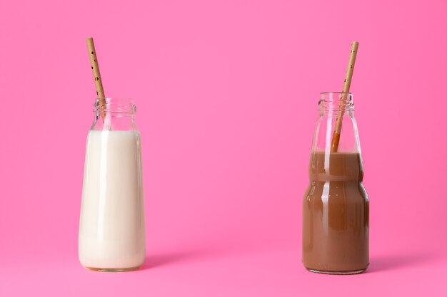 Duas garrafas de vidro de leite ou milkshake contra um fundo rosa close-up