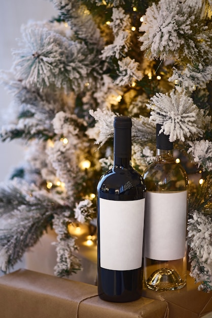 Duas garrafas de vinho com vinho tinto e branco perto da árvore de natal