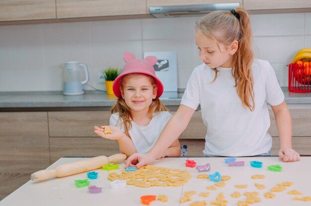 Foto duas irmãs blogueiras estão preparando biscoitos na cozinha e filmando um vídeo de culinária em um smartphone.