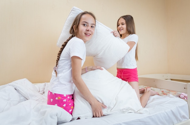 Duas irmãs brigando de travesseiros na cama