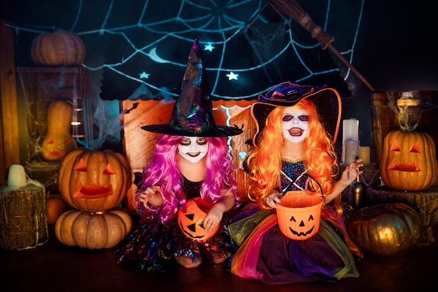 Duas irmãs engraçadas bonitos comemoram o feriado. Crianças alegres em fantasias de carnaval prontas para o Halloween.