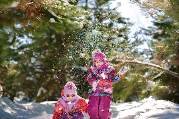 Duas irmãs no inverno em um bosque nevado brincando na neve
