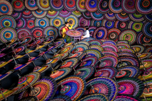 Duas irmãs que fazem guarda-chuvas birmaneses tradicionais Guarda-chuvas coloridos no mercado de rua em Bagan, Myanmar (Burma). Guarda-chuvas birmaneses