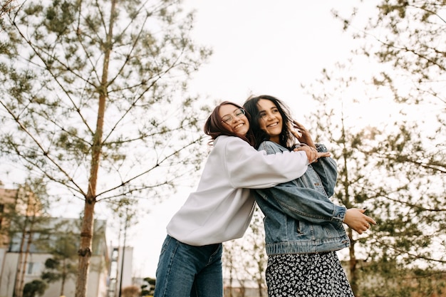 Duas irmãs se divertindo ao ar livre se abraçando e rindo