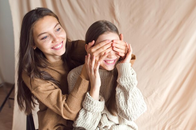 Foto duas irmãs se divertindo no fundo têxtil de cor bege