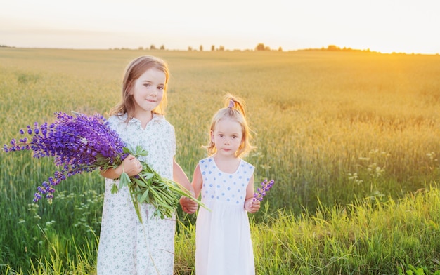 Duas irmãzinhas com flores violetas ao ar livre