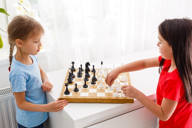 Duas irmãzinhas jogando xadrez em casa