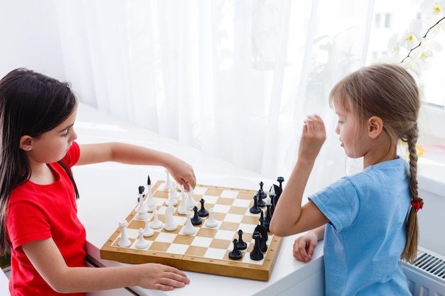 Duas irmãzinhas jogando xadrez em casa