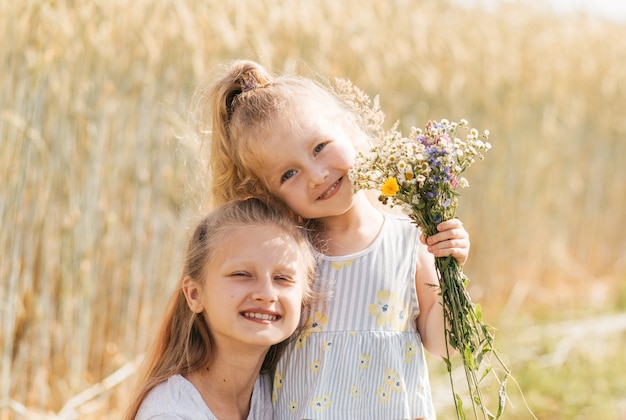 Duas irmãzinhas se abraçam e colhem flores no verão