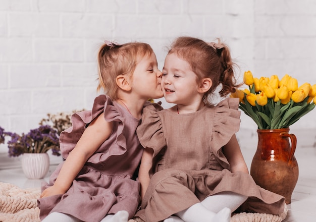 Duas irmãzinhas se beijando em um quarto com flores