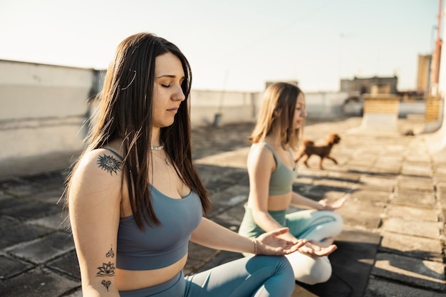 Duas jovem praticando ioga em um terraço.