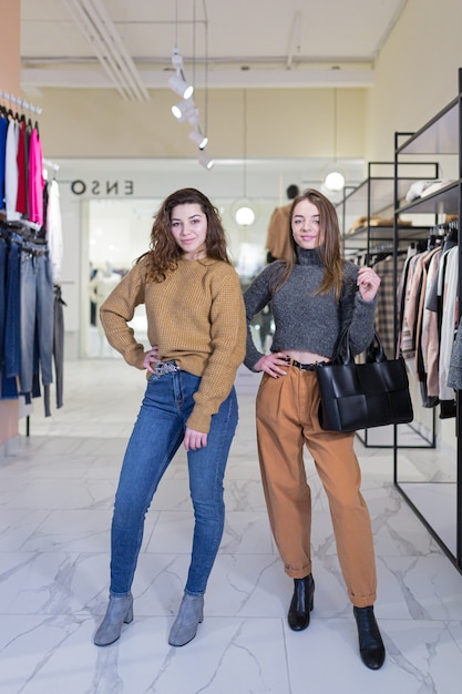 duas jovens amigas se alegram e fazem compras em uma loja de roupas durante as vendas e promoções