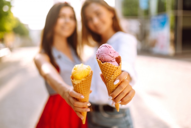 Duas jovens amigas se divertindo e tomando sorvete.