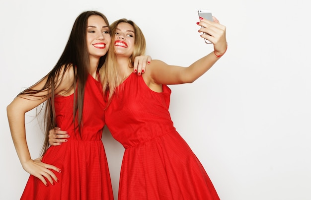 Duas jovens com vestido vermelho tirando uma selfie