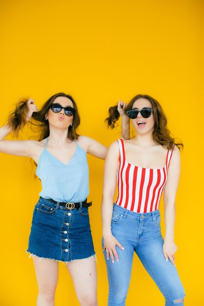 Duas jovens e lindas garotas hipster sorridentes e loiras em roupas de verão da moda Mulheres despreocupadas sensuais
