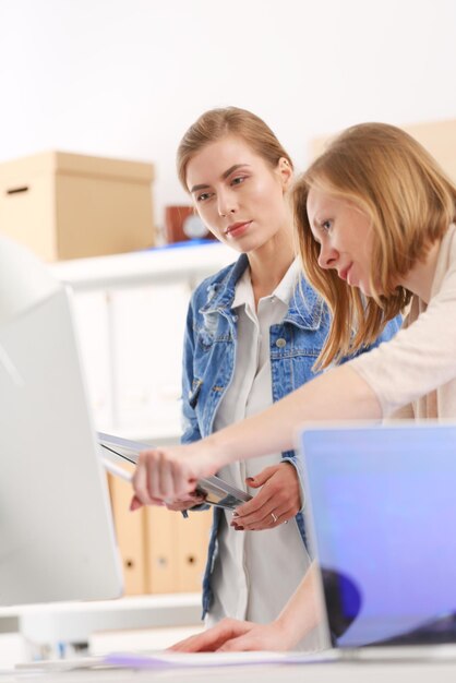 Duas jovens em pé perto da mesa com plano de instrumentos e laptop