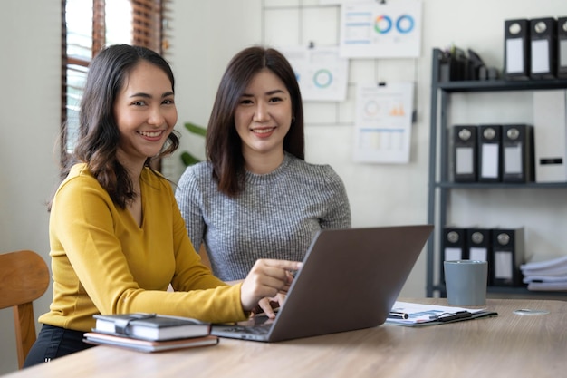 Duas jovens empresárias asiáticas conversam consultam discutem o trabalho com a nova apresentação da ideia do projeto de inicialização analisam o plano de marketing e investimento no escritório