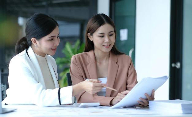 Duas jovens empresárias asiáticas discutem a estratégia de trabalho e planejamento de projetos de investimento Empresários conversando com laptop no escritório