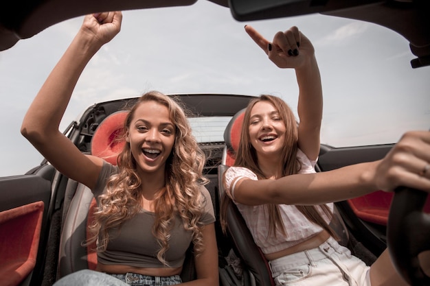 Duas jovens felizes aproveitando o passeio pela liberdade da estrada aberta