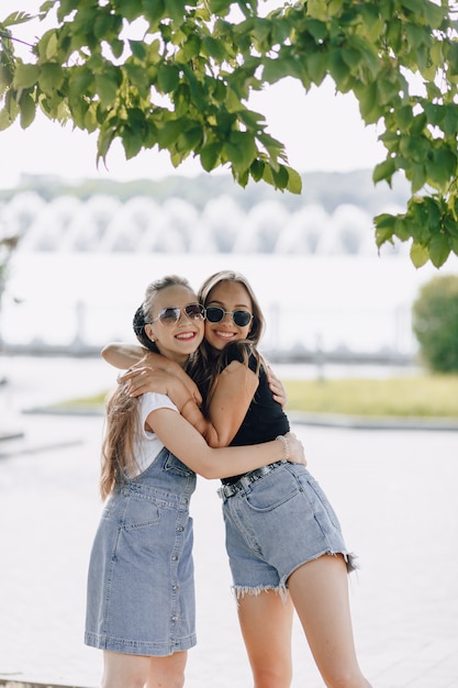 Foto duas jovens garotas bonitas em uma caminhada no parque. um dia ensolarado de verão, alegria e amizades.