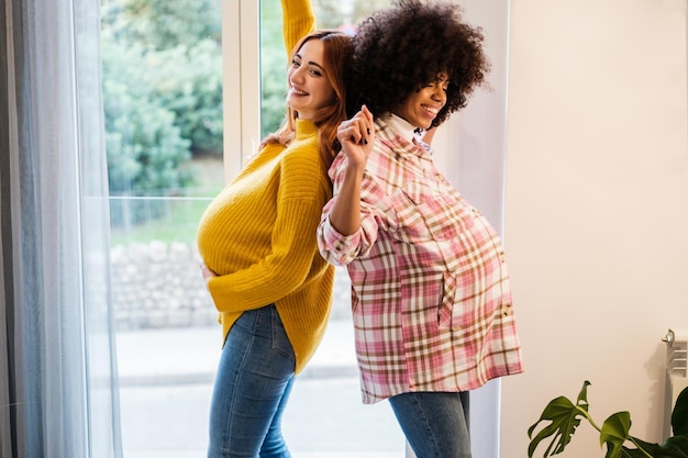 Duas jovens grávidas passando tempo dançando juntas Conceito maternidade lealdade amizade