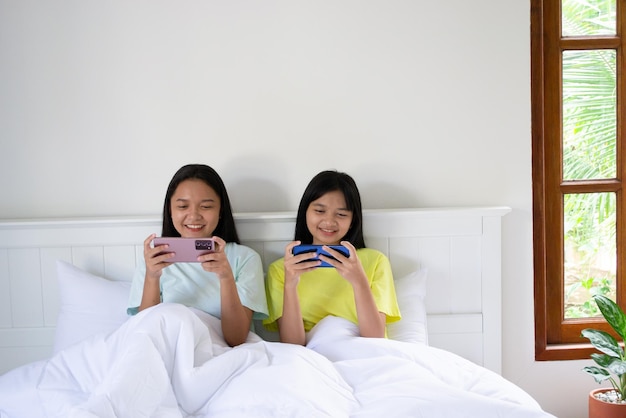 Duas jovens jogando com smartphone no quarto em casa