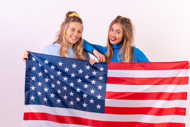 Duas jovens loiras caucasianas retrato de bandeira americana sorrindo isoladas em um fundo branco