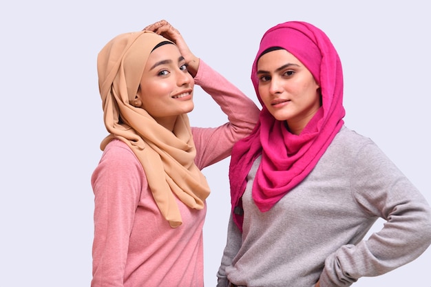 duas jovens muçulmanas usando hijab e posando sobre um fundo branco modelo indiano do paquistanês