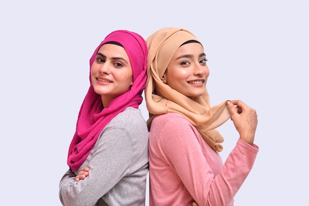 duas jovens muçulmanas usando hijab sorrindo, posando para a câmera do modelo indiano do paquistanês