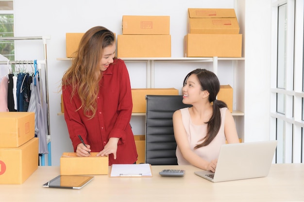 Duas jovens mulheres de negócios estão discutindo alegremente planos de marketing on-line em seu escritório em casa