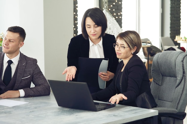 Duas jovens mulheres de negócios no escritório, analisando informações olhando para um laptop.