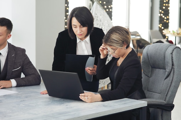 Duas jovens mulheres de negócios no escritório, analisando informações olhando para um laptop.