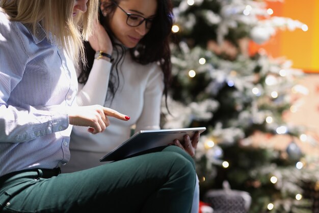 Duas jovens mulheres sorridentes comprando online para o Natal, comprando presentes para o conceito de ano novo