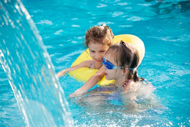 Duas jovens sorridentes em uma piscina com água azul clara em óculos de natação azuis Férias de verão