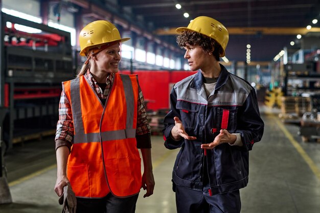 Duas jovens trabalhadoras da fábrica moderna discutindo pontos de trabalho