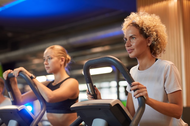 Duas jovens treinando em esteiras em uma academia moderna