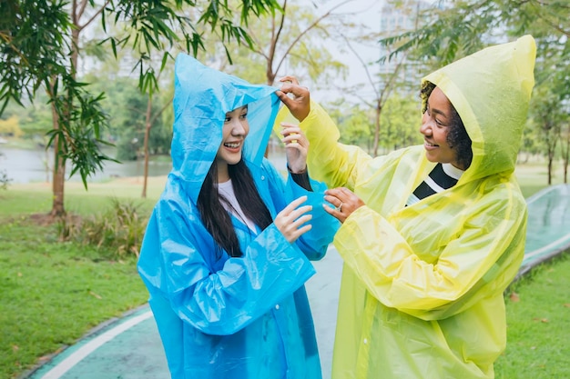 Duas jovens vestindo capas de chuva estão se divertindo juntas na chuva ao ar livre no jardim