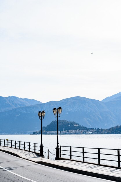 Duas lâmpadas de rua nas margens do lago de como, na itália, com vista para a montanha.